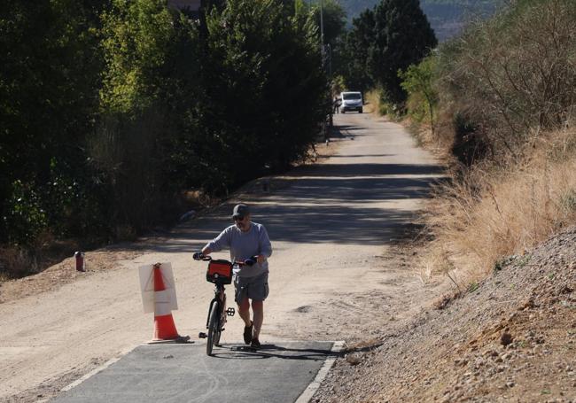 Un ciclista se baja de la bici para salvar el desnivel en el único tramo de carril bici que alcanza el camino de Hornillos.